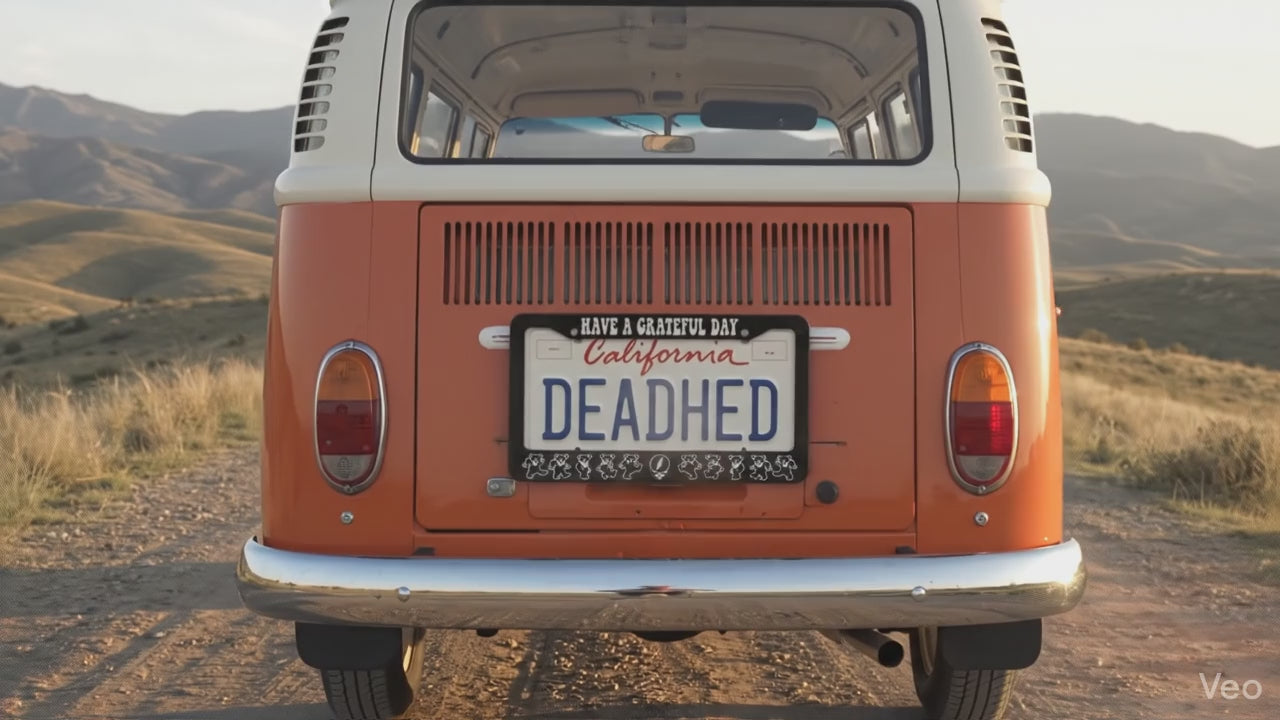 Orange retro hippie van on gravel road driving through grassy hills